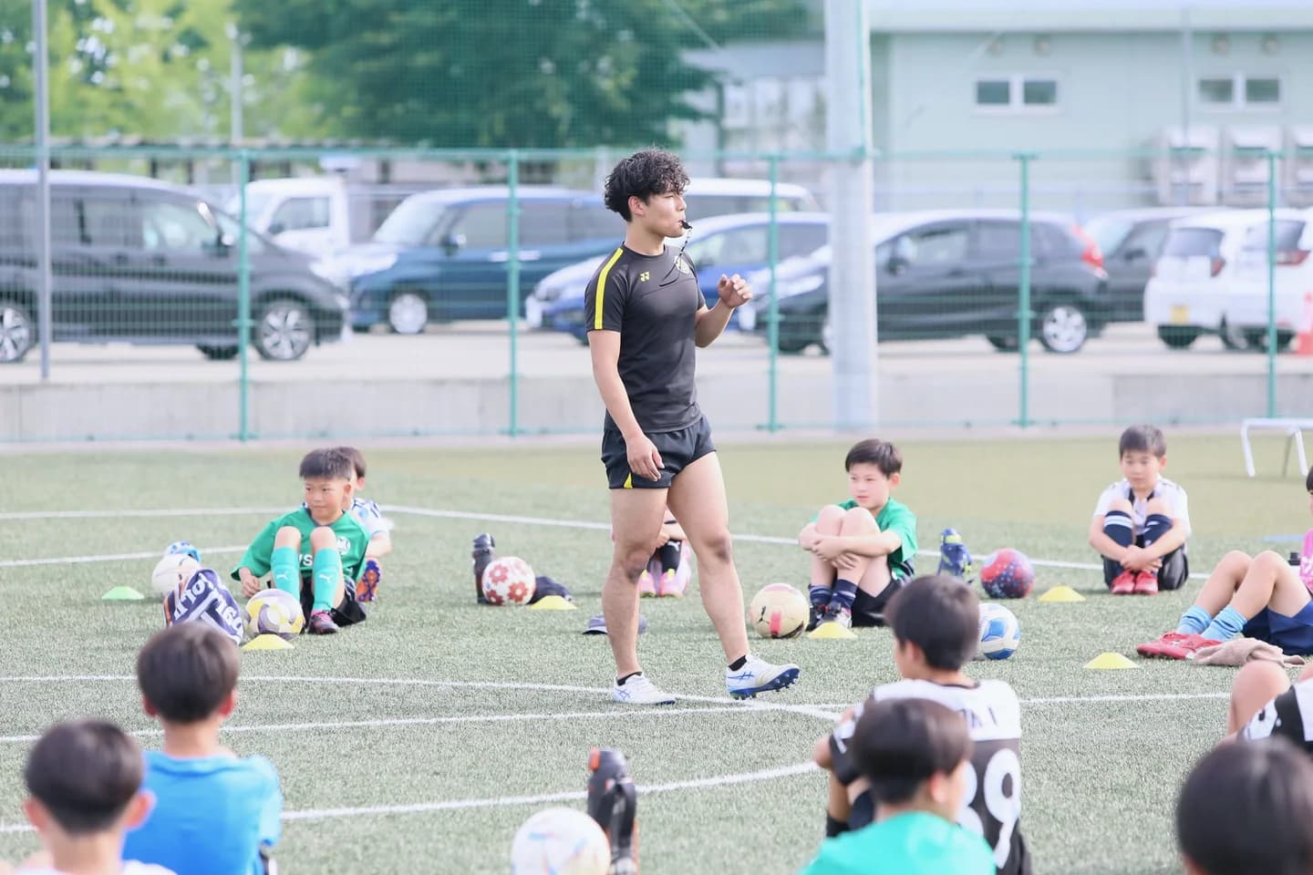 講習会で、ボールを持って座る選手たちに説明する高橋